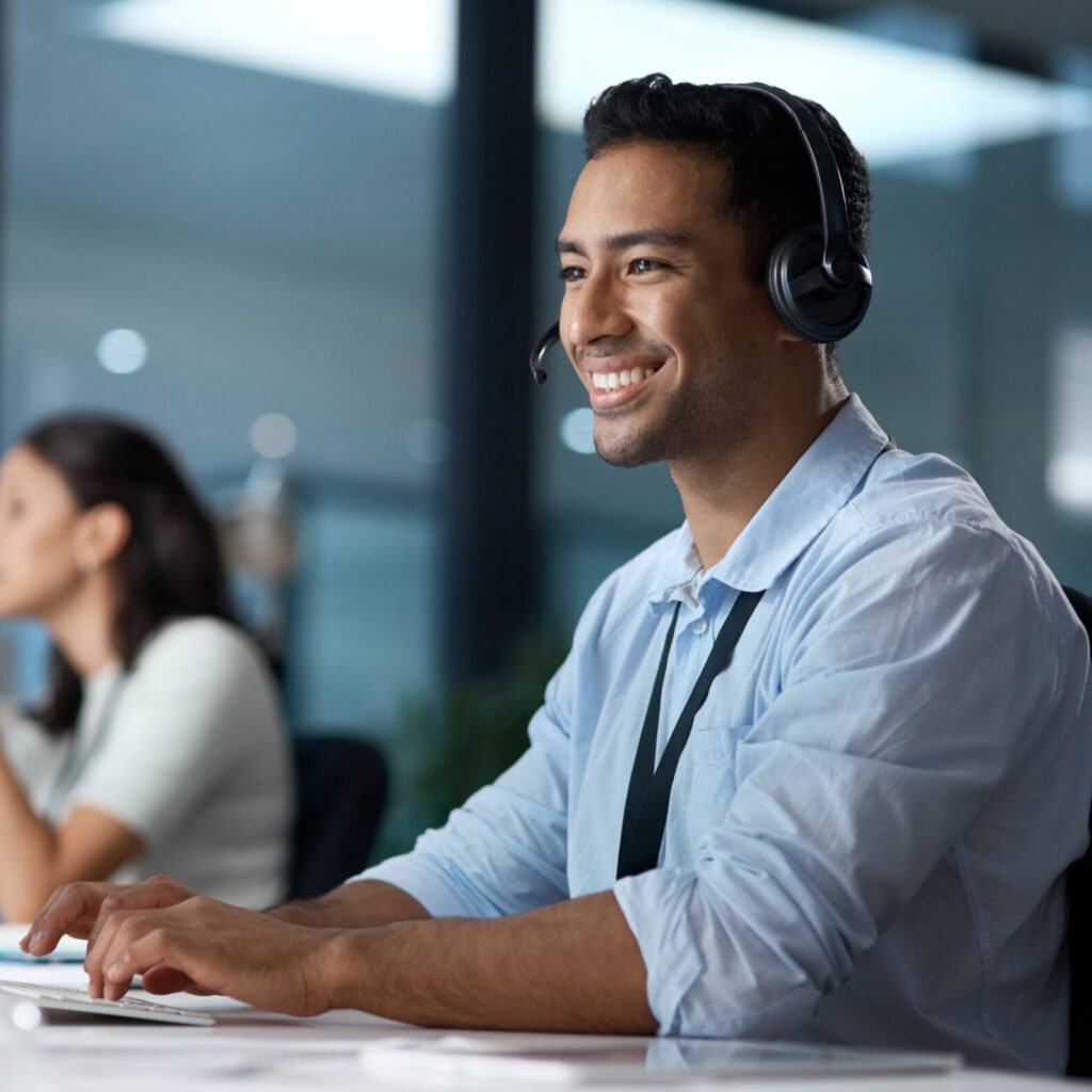 shot of a young man using a headset and computer in a modern office.